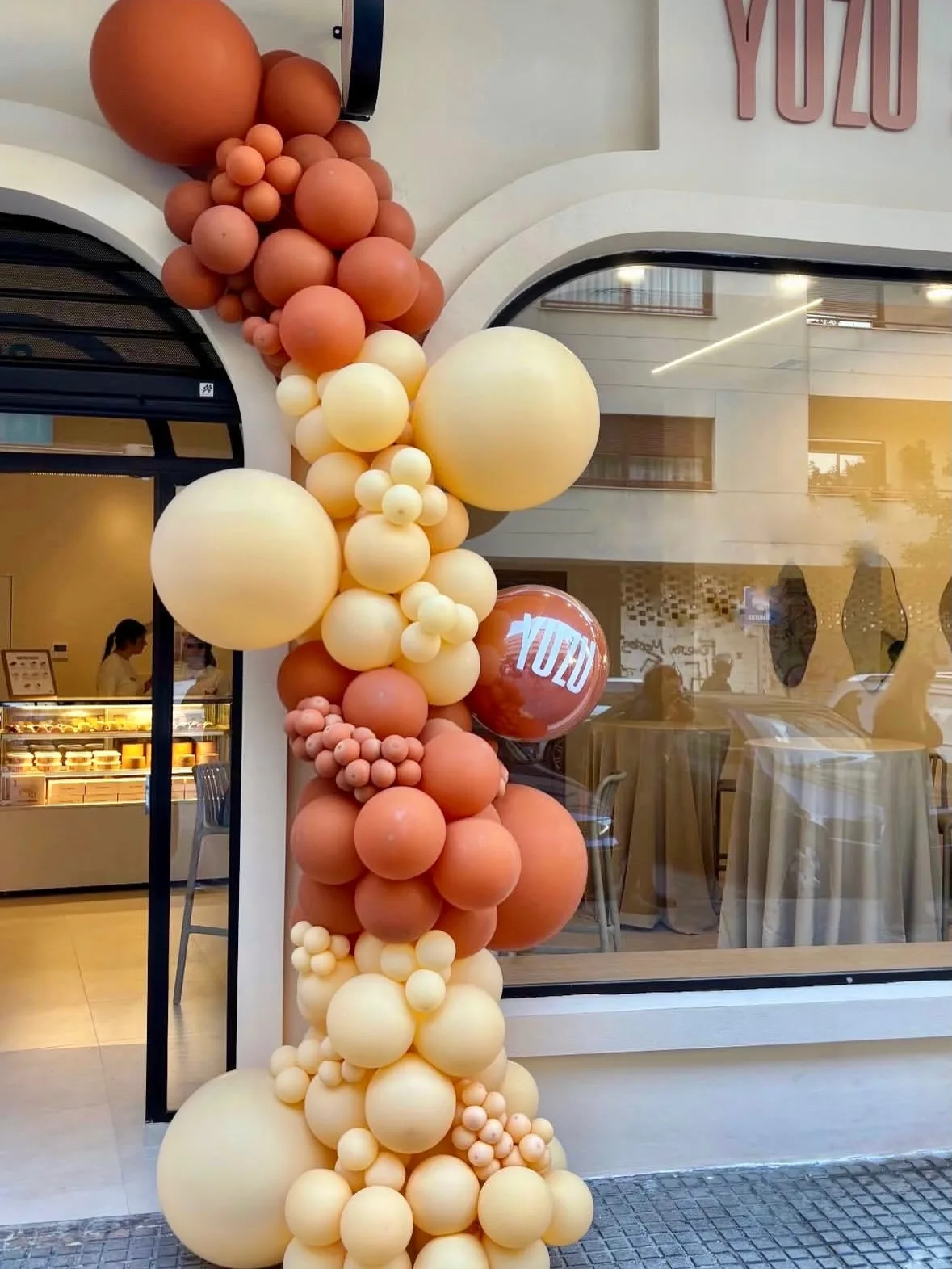 Columna orgánica de globos en tonos terracota y beige para una inauguración en Málaga