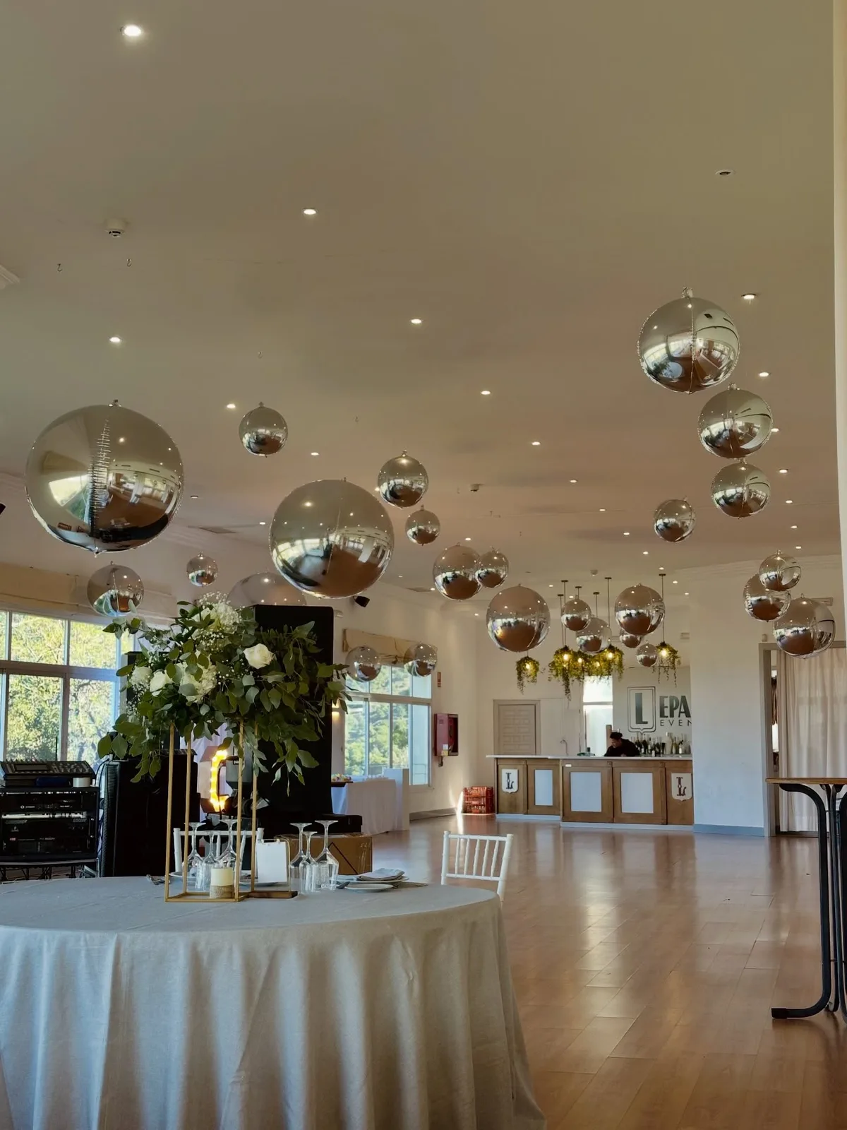 Salón de boda con globos metalizados suspendidos y mesa decorada en Málaga