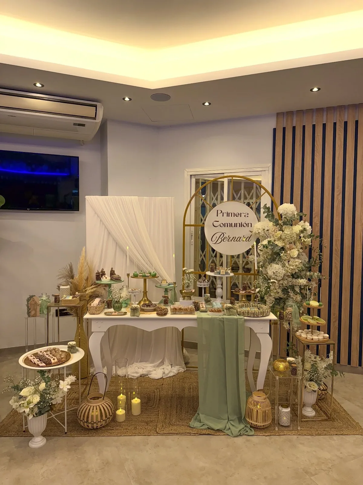 Mesa dulce de comunión en tonos verdes con flores y velas en Málaga