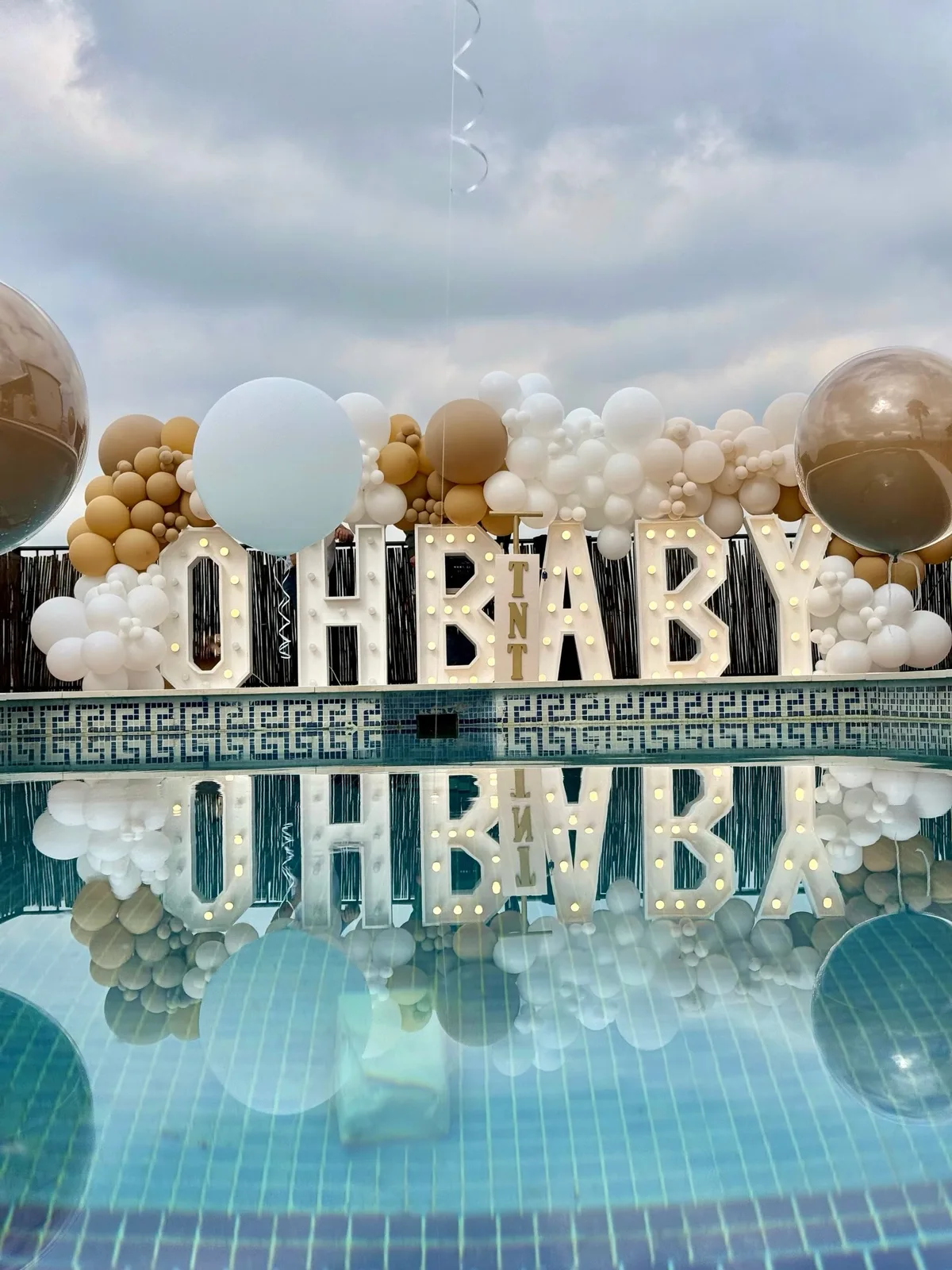 Decoración Oh Baby junto a una piscina con globos en tonos neutros en Málaga