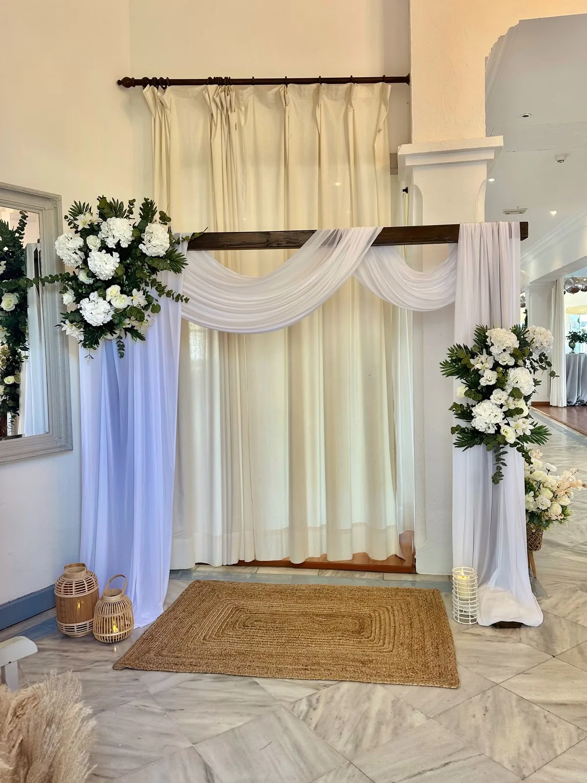 Arco de ceremonia de boda con telas blancas y flores en Málaga
