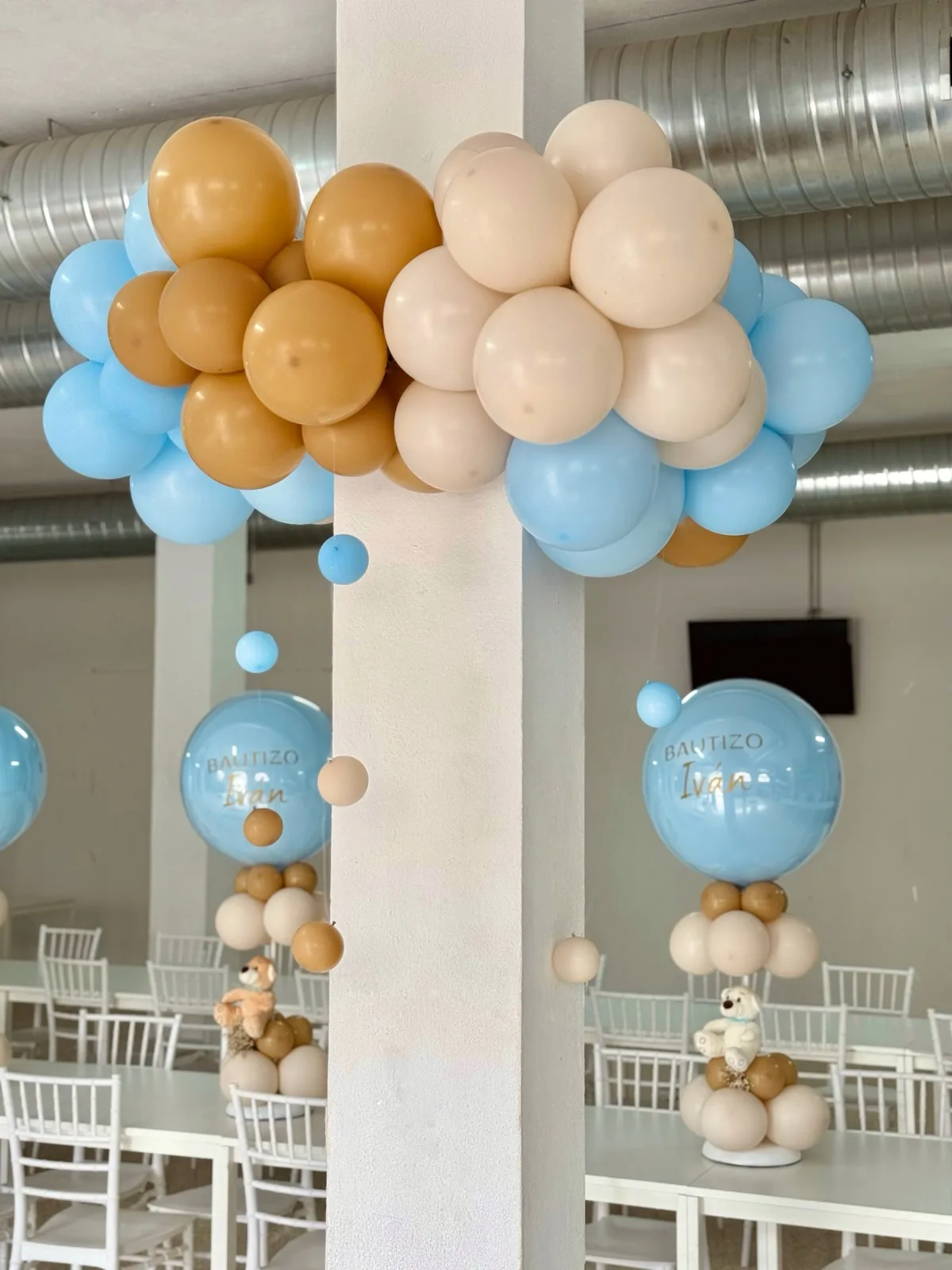 Entrada de bautizo con globos azules y beige y centros decorativos en Málaga