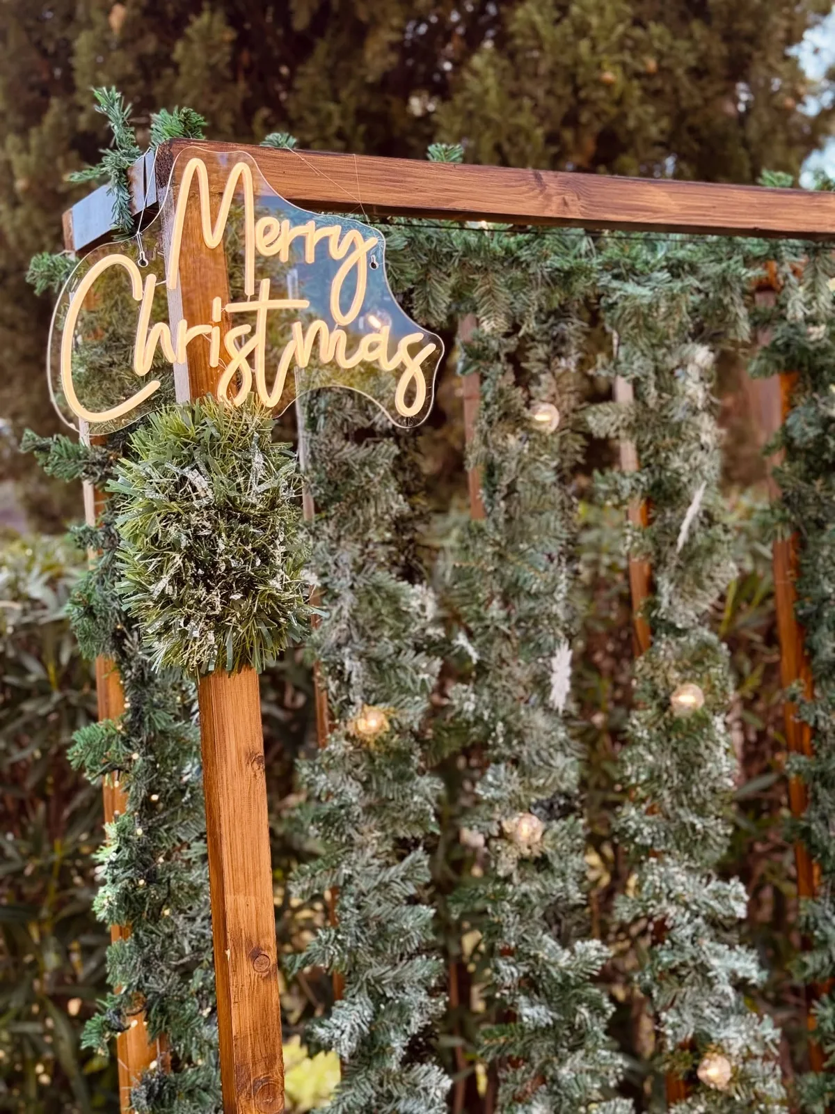 Rincón navideño corporativo con fondo vegetal y letrero luminoso en Málaga