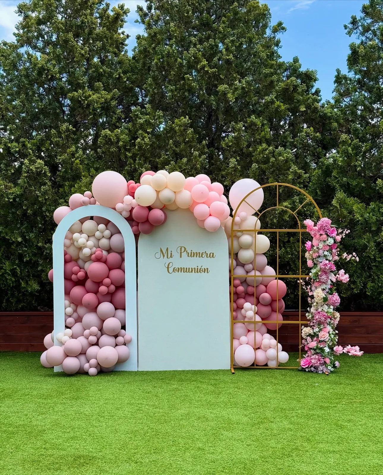 Photocall de comunión en un jardín con globos rosas y flores en Málaga
